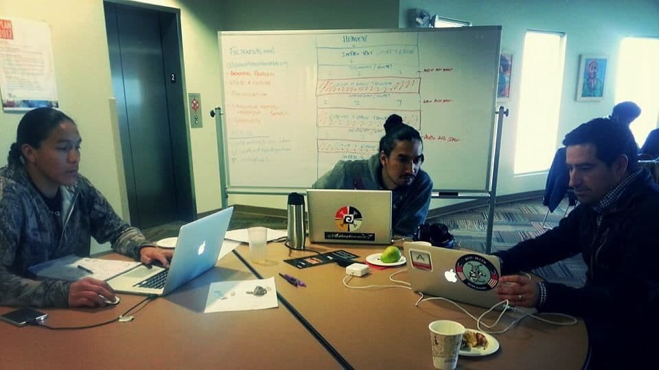 The Coyote & Eagle team building the platform at the 2014 NDN Hackathon — laptops open, whiteboard behind them.
